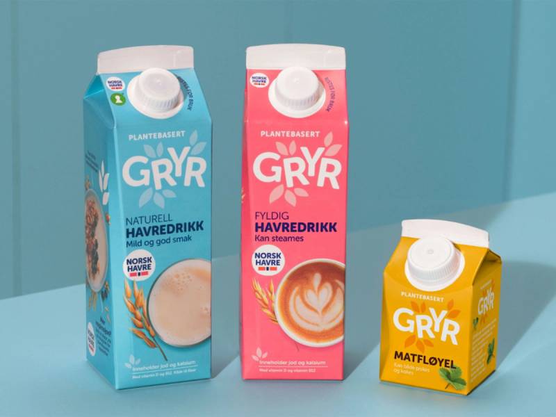 Tre melkekartonger med Gryr-merke, i blå, rosa og gul farge, plassert mot en blå bakgrunn.