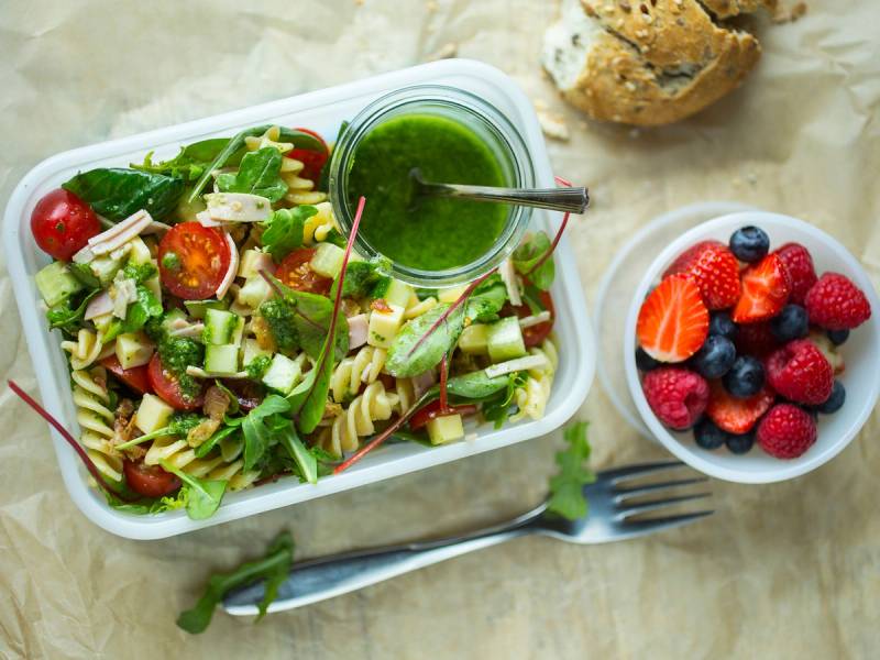 Pastasalat med pesto, ferske grønnsaker og en skål med bær ved siden av