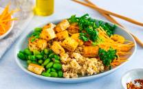 En tallerken med tofusalat med havreris, tofu i terninger, grønne erter, revet gulrot og frisk persille, med spisepinner ved siden av.