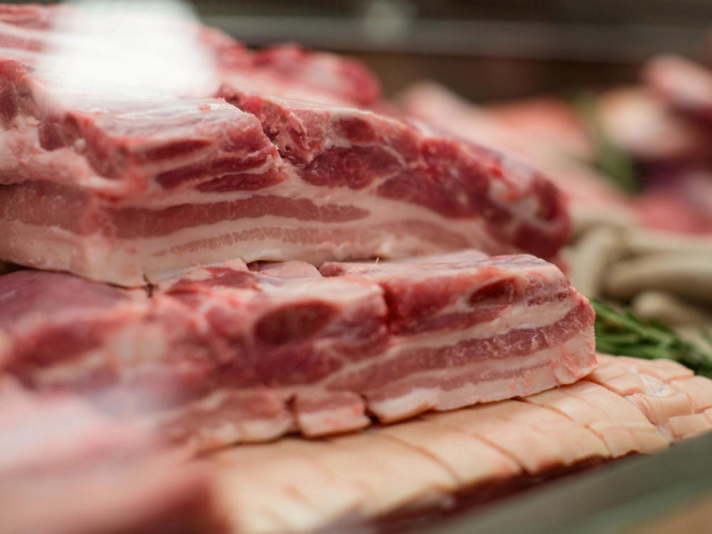 Ulike typer kjøtt, inkludert bacon og skiver av annet kjøtt, lagt ut på en kjøttdisk.