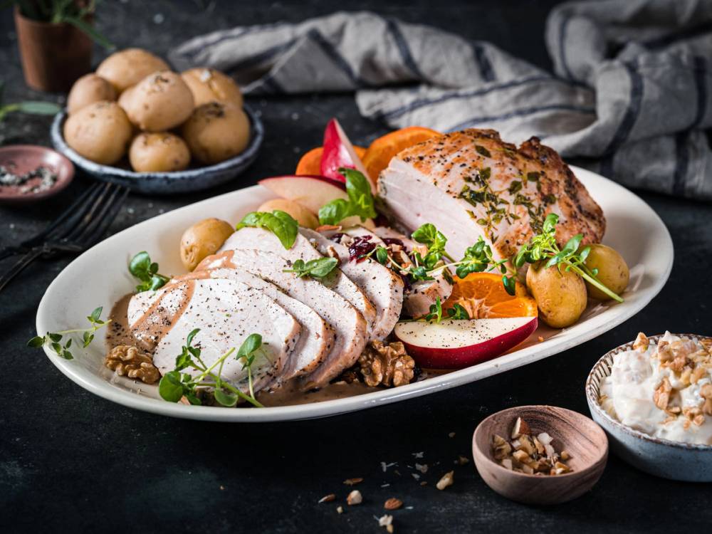 Kalkunbryst servert med poteter, grønnsaker og saus på et hvitt fat.