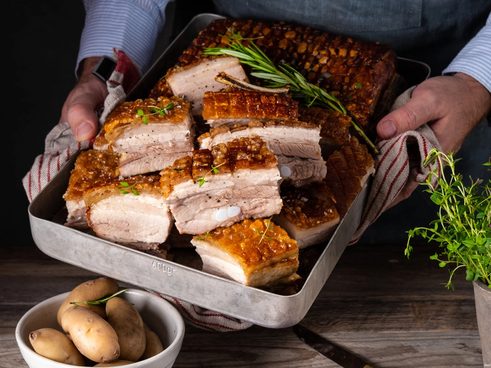 Ribbe med sprø svor og grønne urter på et fat, klar til servering.