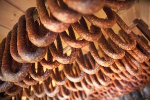 Nærbilde av rustne jernlenker hengt opp i en kjede, med fokus på teksturen og overflaten.