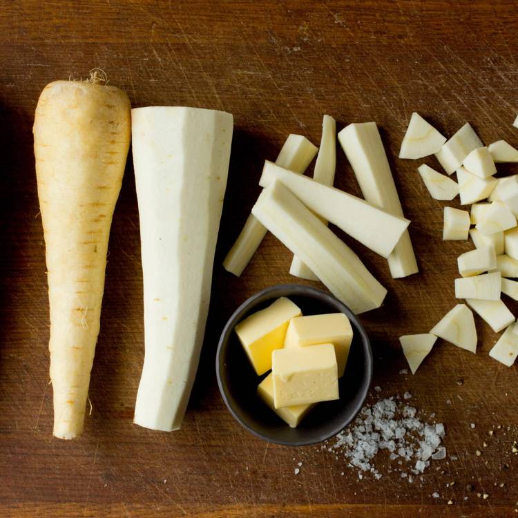 Pastinakk, smør og salt på et trebord, klare til å bli laget til puré.