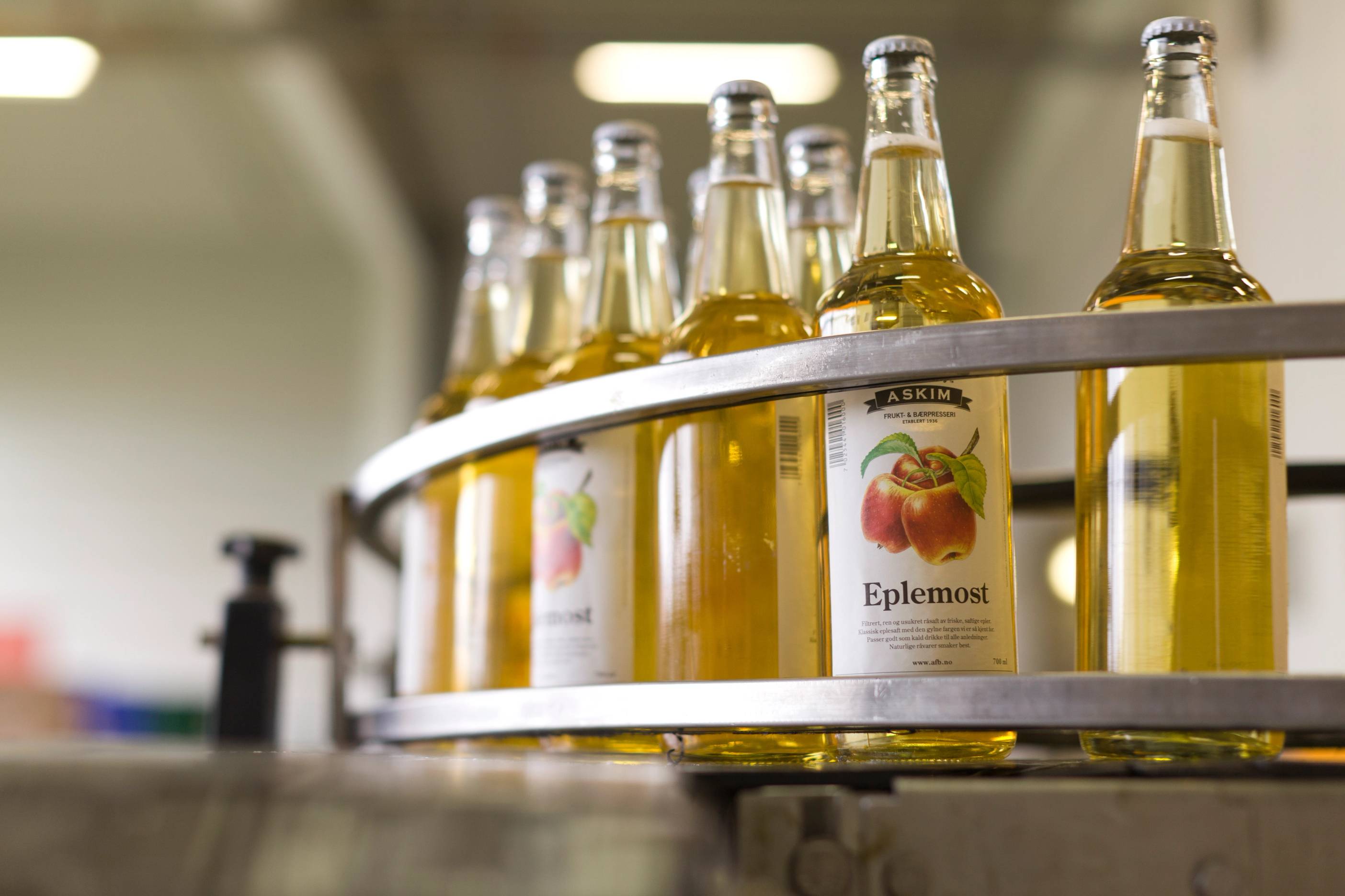 Flasker med eplemost på en produksjonslinje ved Askim frukt- og bærpresseri.