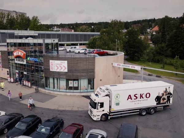 Norgesgruppen Meny butikk med parkeringsplass og en Askø-lastebil foran.
