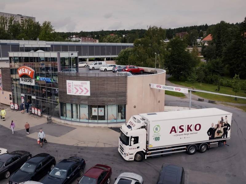 Norgesgruppen Meny butikk med parkeringsplass og en Askø-lastebil foran.