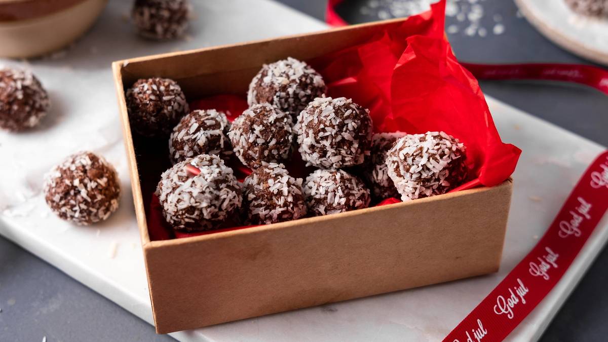 Bountyboller i en liten eske med rødt papir, omgitt av julepynt og gavebånd.