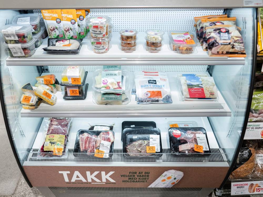 Frossenmat i en kjøledisk på en dagligvarebutikk, med ulike pakker og merker av kjøtt og ferdigmat.