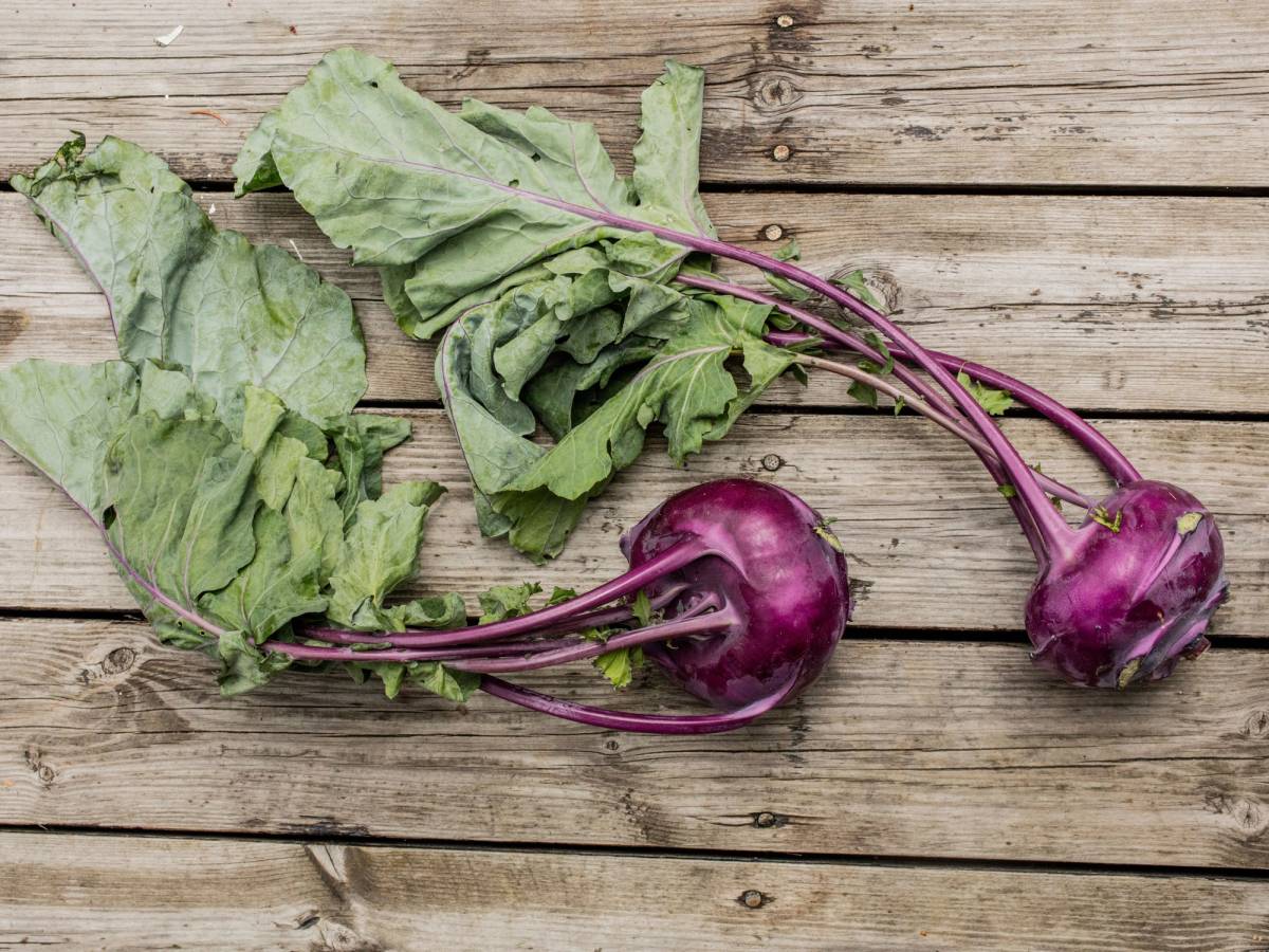 To lilla knutekål med grønne blader ligger på en treplate.