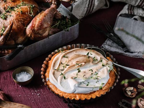 En kalkun er stekt og ser ut til å være klar for Thanksgiving-middag, omgitt av tilbehør og pynt.