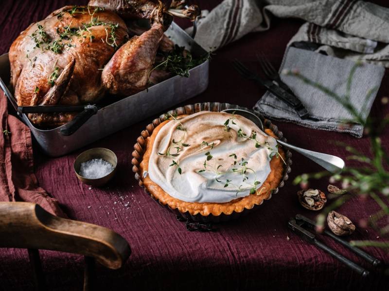 En kalkun er stekt og ser ut til å være klar for Thanksgiving-middag, omgitt av tilbehør og pynt.