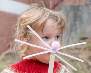 Barn med påskeegg og påskepynt i håret, som deltar i påskeaktivitet utendørs.