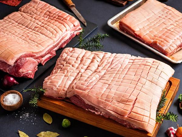 Ulike stykker ribbe på et kjøkkenbord med julepynt og tilbehør rundt.