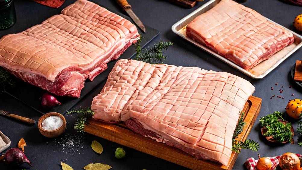 Ulike stykker ribbe på et kjøkkenbord med julepynt og tilbehør rundt.