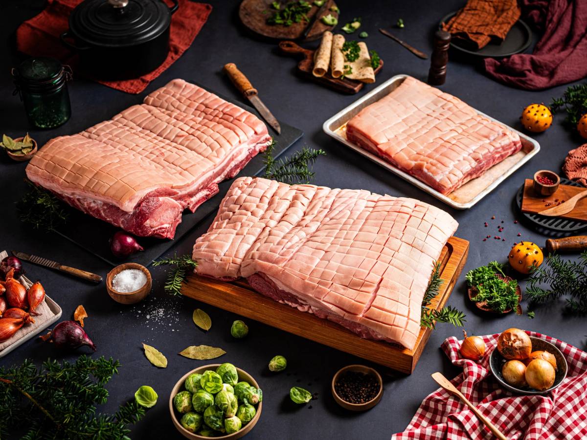 Ulike stykker ribbe på et kjøkkenbord med julepynt og tilbehør rundt.