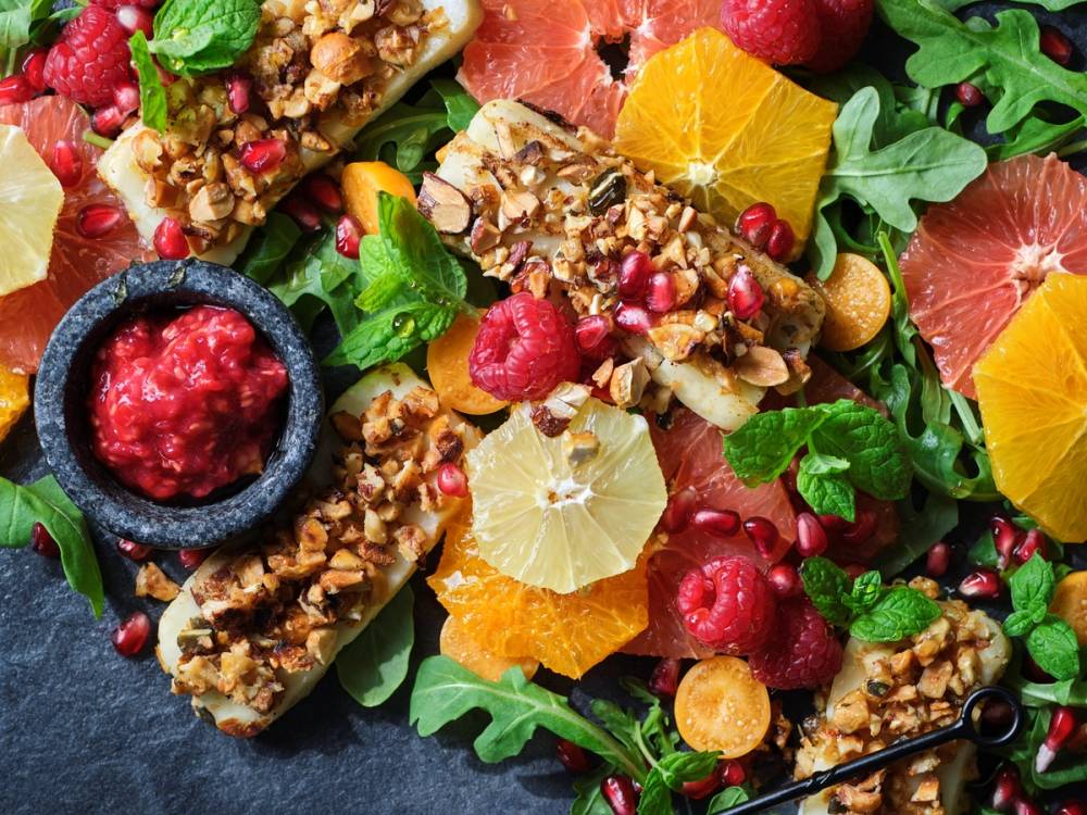 Fargerik fruktsalat med sitrusfrukter, bær og granola, pyntet med mynteblader.