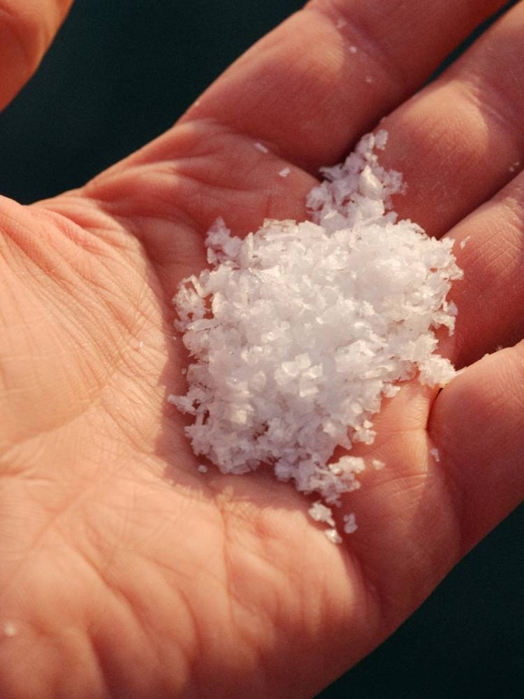 Hånd som holder en klump med havsalt eller snøkrystaller.