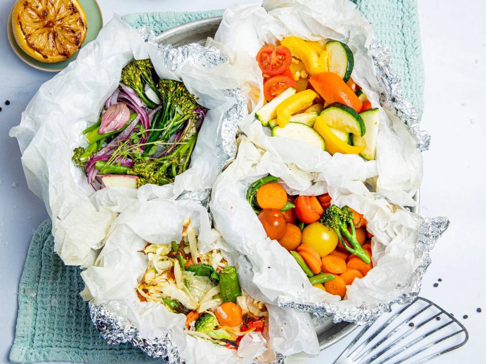 Grillede grønnsaker i aluminiumsfolie med salat ved siden av.
