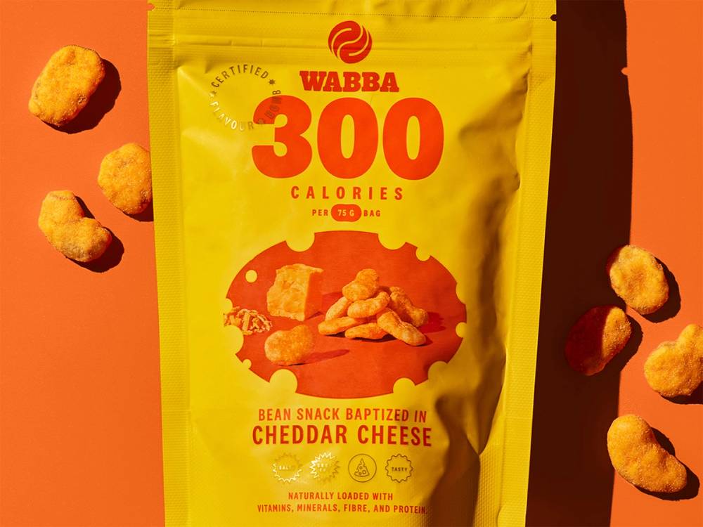 Pose med Wabba cheddar cheese snacks og noen enkeltbiter rundt på en oransje bakgrunn.