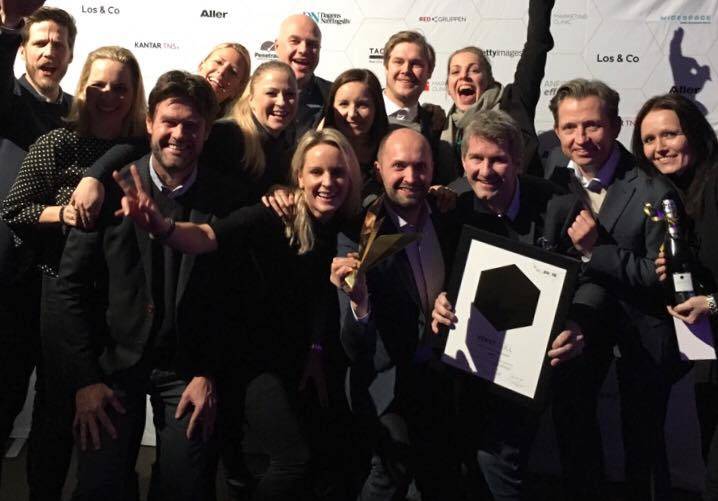 En gruppe mennesker som står sammen på en utstilling eller et arrangement, noen holder plakater eller bilder, og alle har ansiktene dekket til for anonymitet.