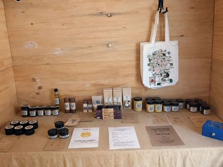 A timber honesty stall at Haaseford Farms Garlic in Ironbank, with jars of black garlic, minced garlic and garlic paste, brown paper bags and handwritten price signs