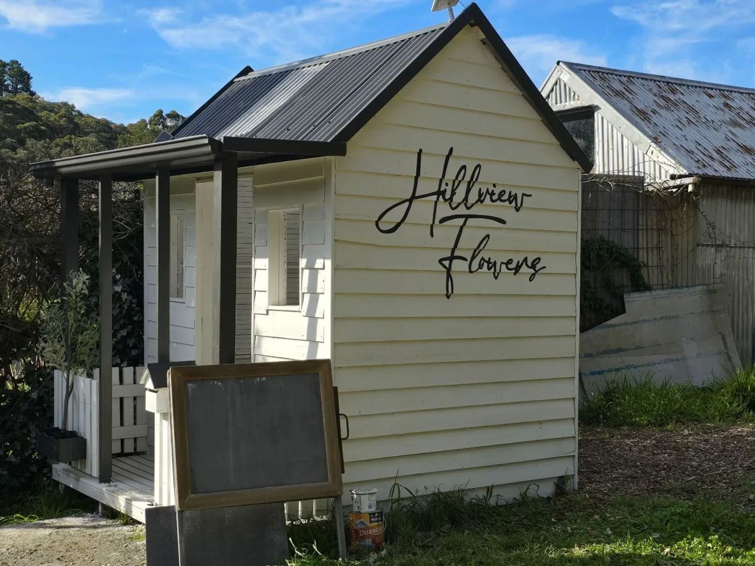 The cream weatherboard flower shed at Hillview Flowers in Mylor, the stall name hand-painted on the side