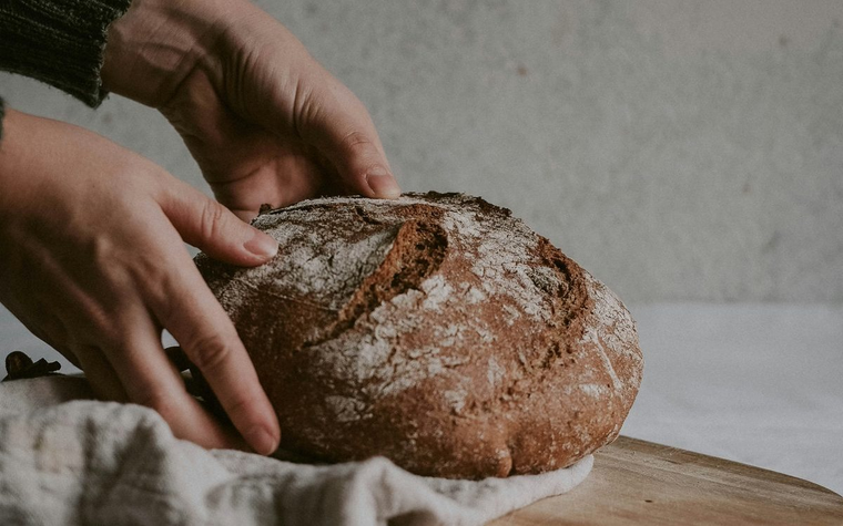 Hands holding a rustic home-baked loaf of bread