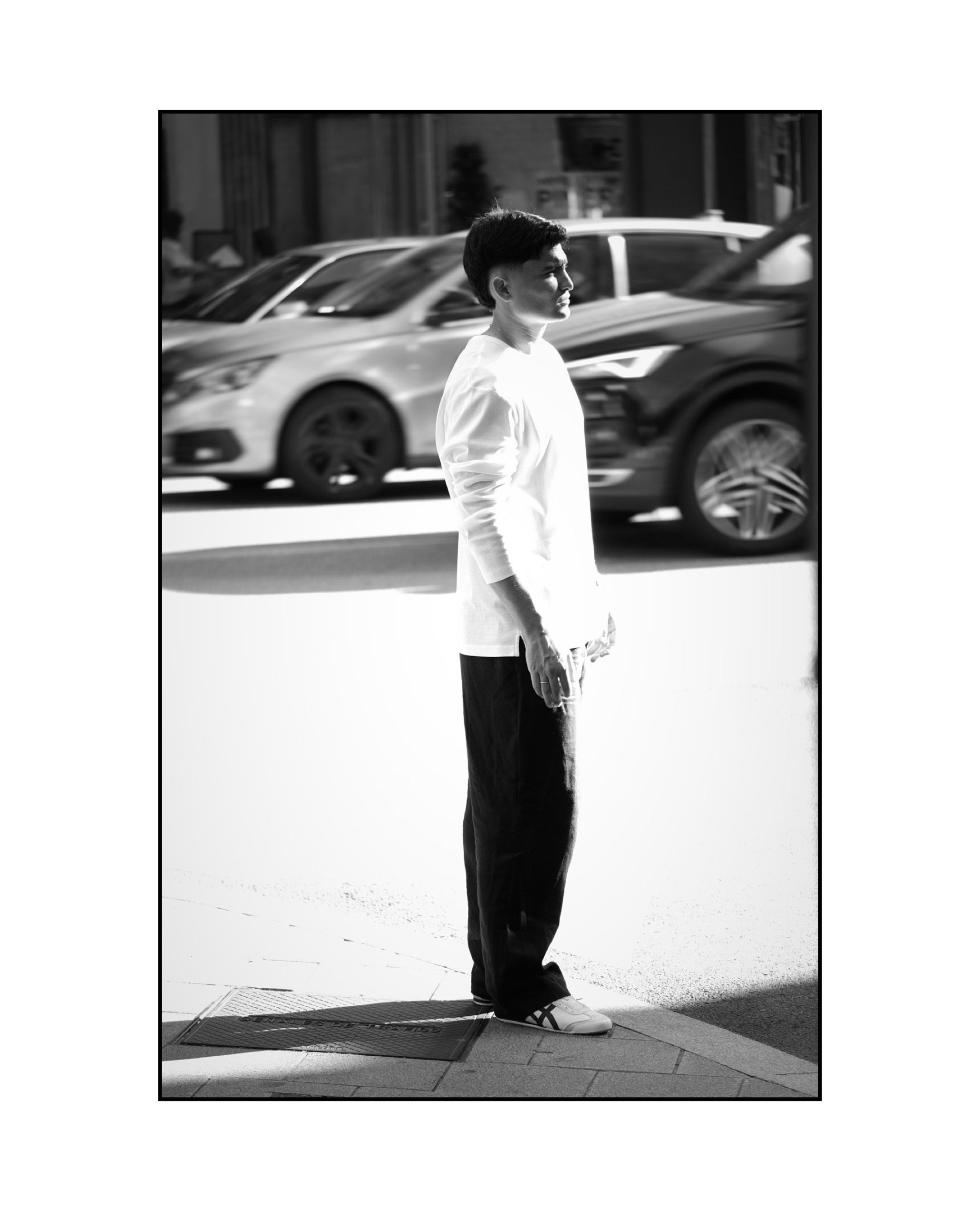Aritz Aldasoro de perfil en una esquina, con coches en movimiento detrás, en blanco y negro.