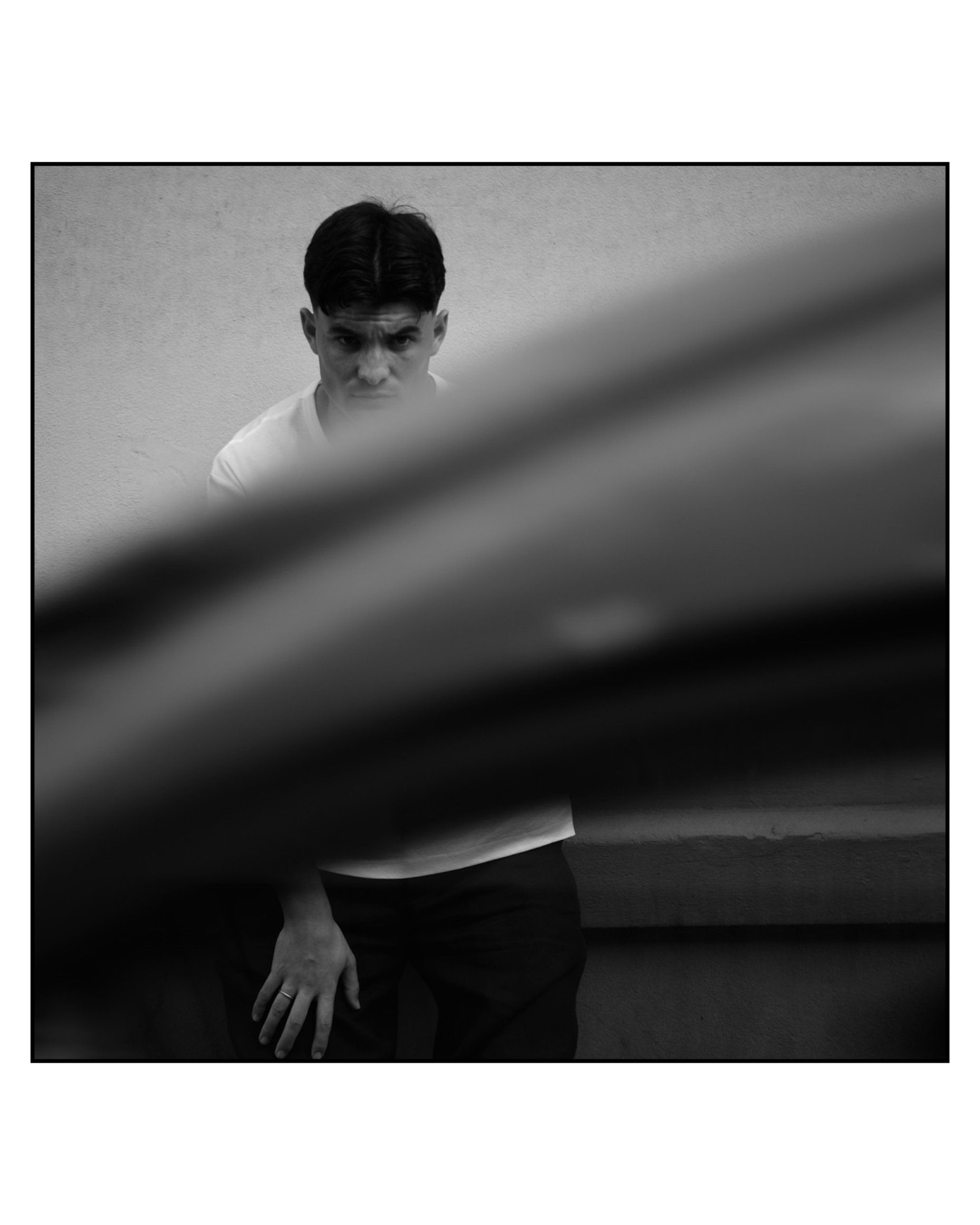 Aritz Aldasoro fotografiado a través de la carrocería desenfocada de un coche, en blanco y negro.
