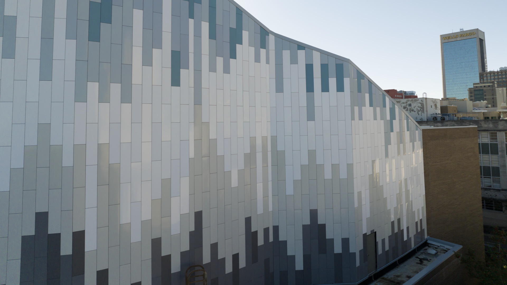 a building with a gray and white facade and a yellow building in the background