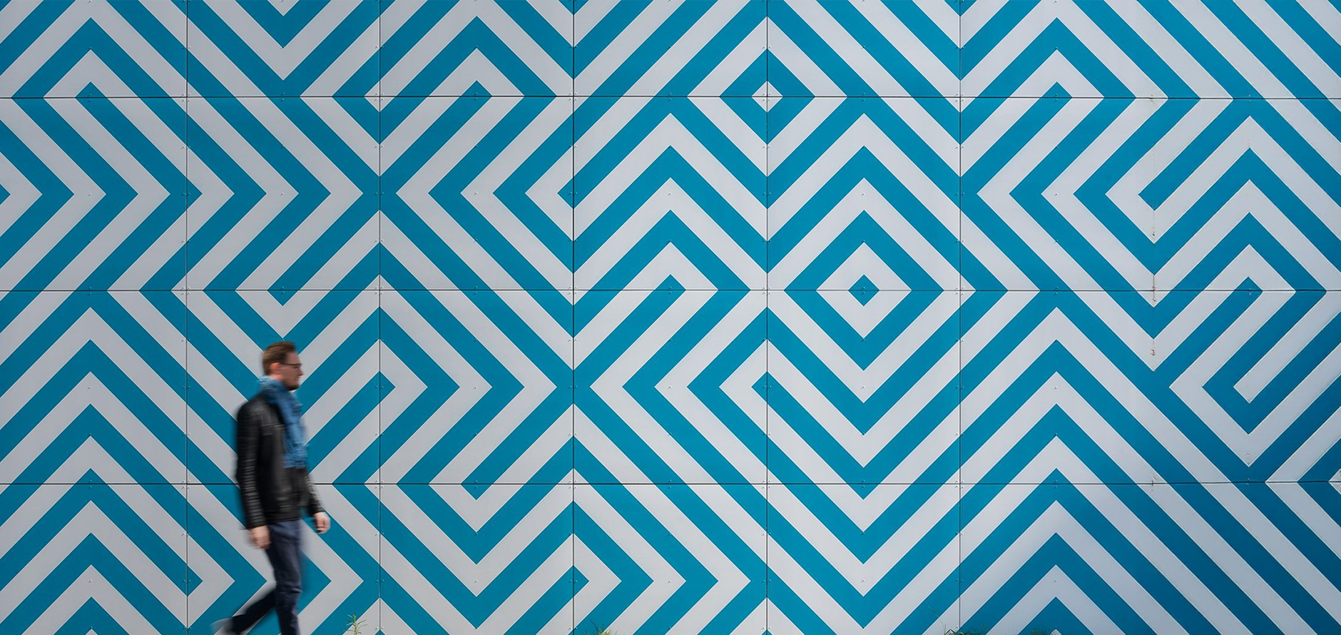 a man walks in front of a blue and white geometric pattern