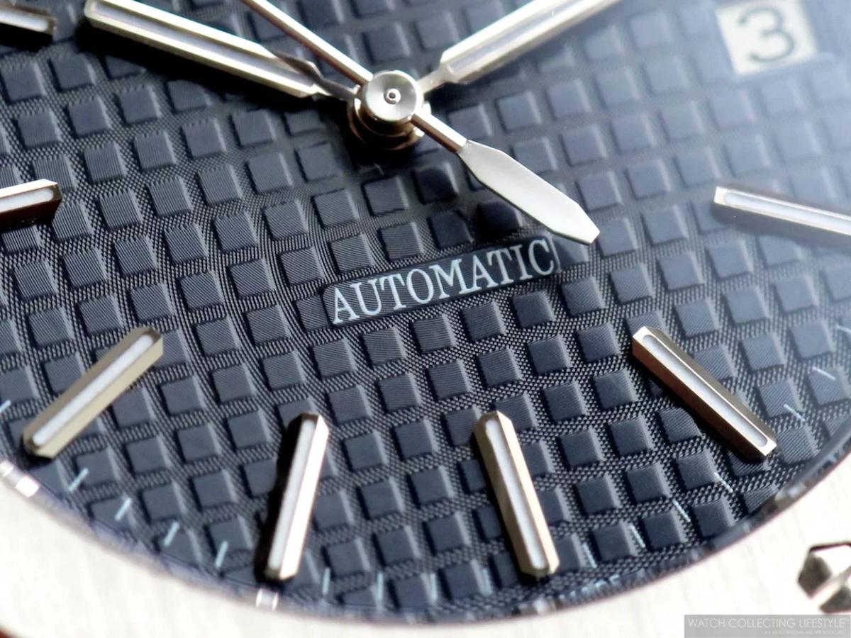 The Sovereign Object: An authentic stainless steel Audemars Piguet Royal Oak with a navy face, representing the material singularity and dense design heritage being systematically evacuated by the drop's bioceramic counterpart.