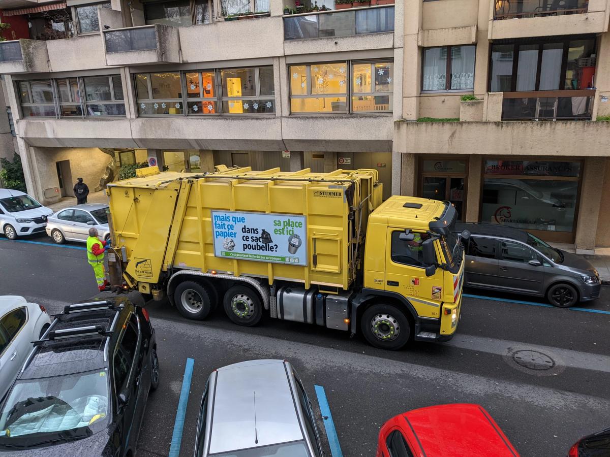 A municipal refuse collection truck at work on a city street.