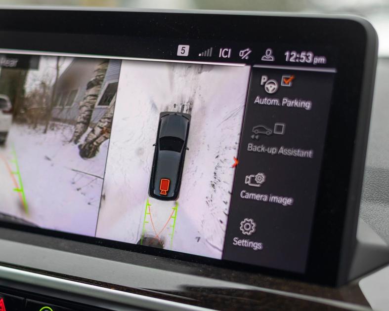 A car infotainment screen filling the frame, displaying a surround-view parking camera image, with no manufacturer badge visible.