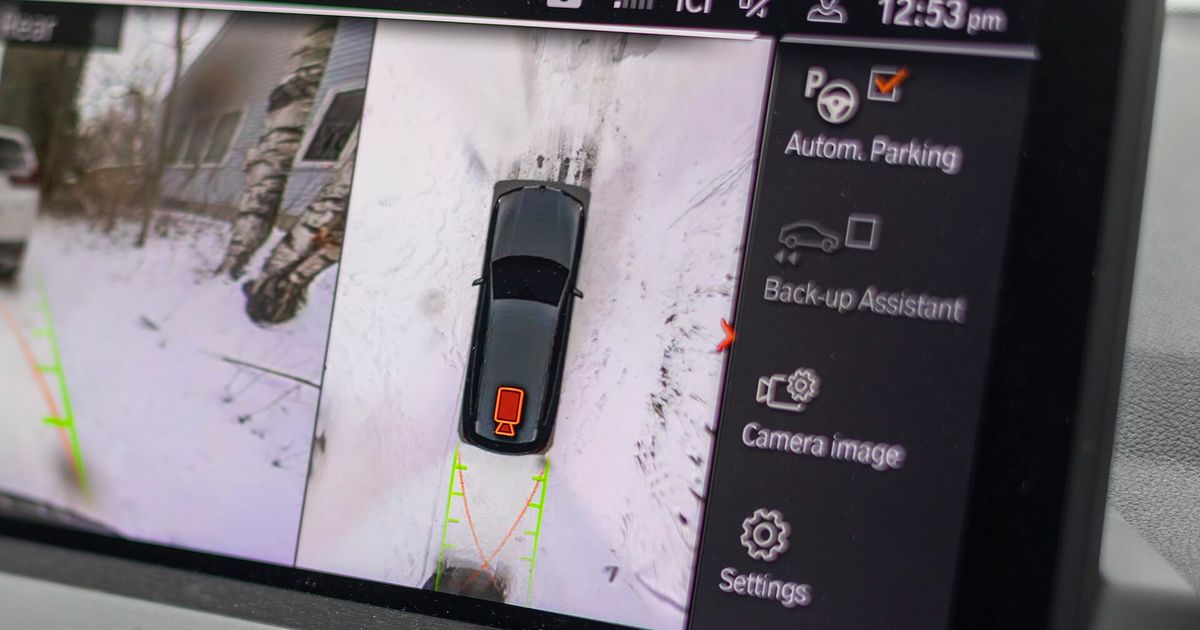 A car infotainment screen filling the frame, displaying a surround-view parking camera image, with no manufacturer badge visible.