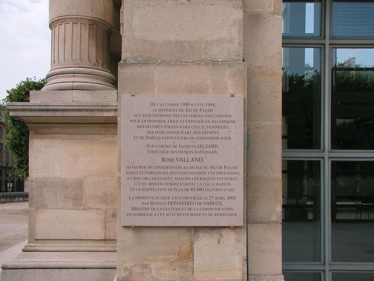 A pale stone commemorative plaque mounted on the wall of a building, carrying several paragraphs of engraved French text.