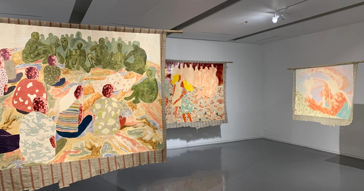 Nengi Omuku paintings installed at the Bangkok Art Biennale 2022 at JWD Art Space, showing multiple oil paintings on sanyan textile depicting collectivized figures.
