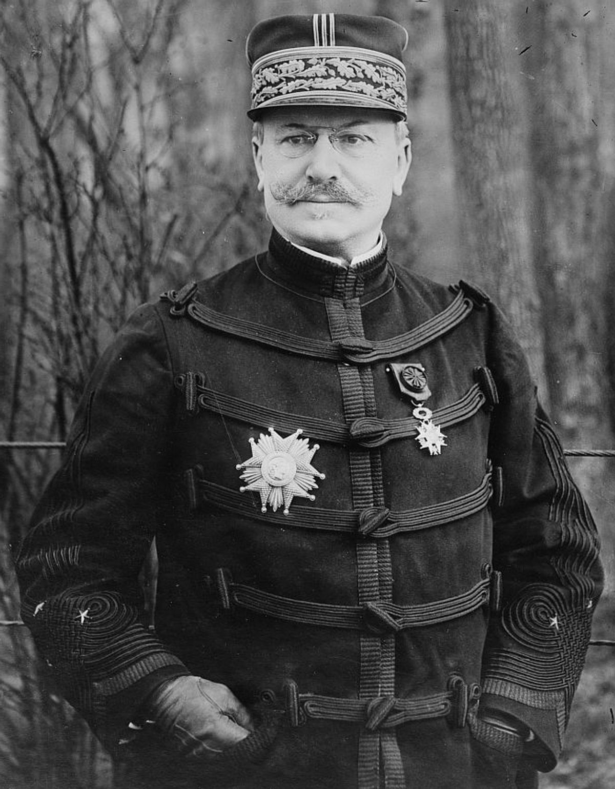 A studio photograph of a moustached officer in a dark braided uniform and kepi, wearing a large star decoration.