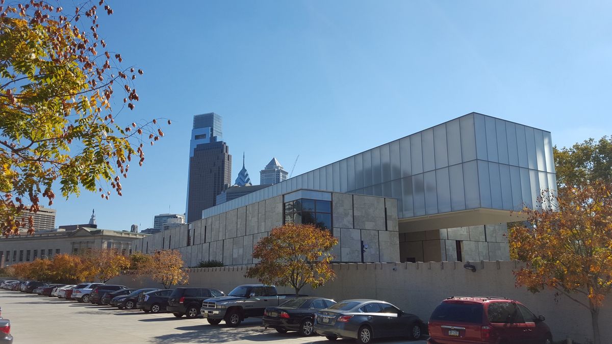 The exterior of the Barnes Foundation building in central Philadelphia, a long low structure faced in pale stone behind a paved forecourt.
