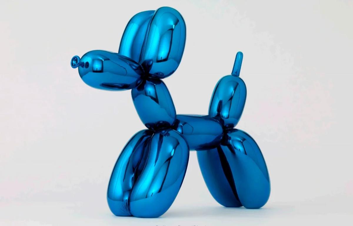 A large mirror polished blue steel sculpture in the form of a twisted balloon dog, lit against a plain pale background.