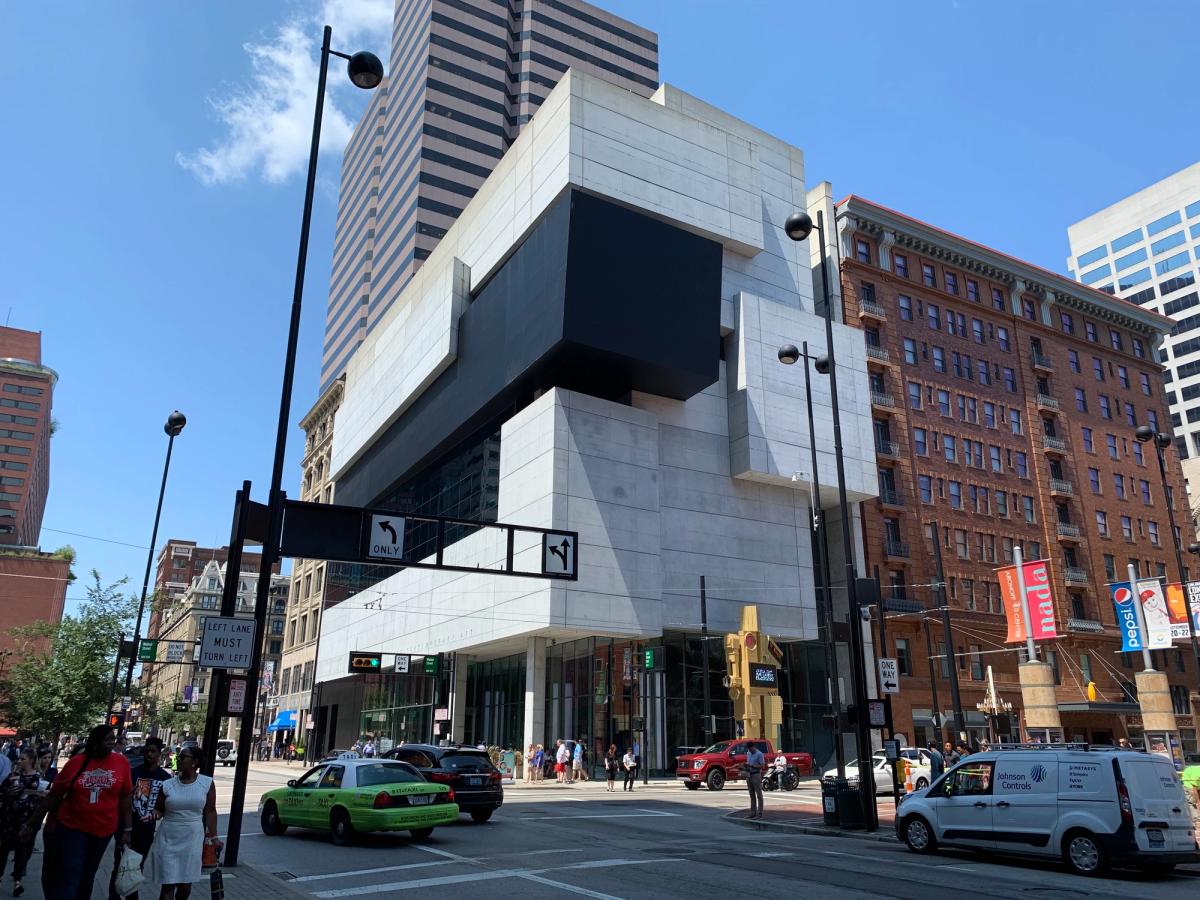 A low modern museum building of stacked offset concrete and glass volumes on a city street corner.
