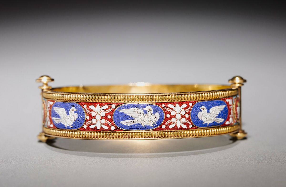 A gold bracelet photographed against a dark background, museum collection object.