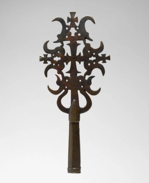 An Ethiopian metal processional cross with elaborate openwork tracery radiating from a central cross form.