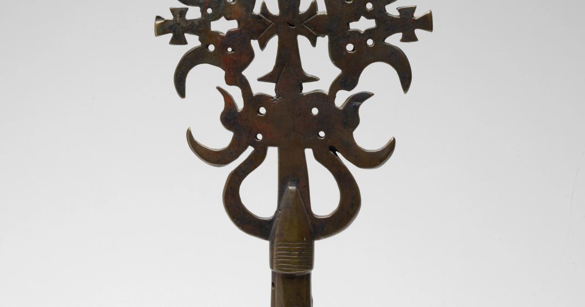 An Ethiopian metal processional cross with elaborate openwork tracery radiating from a central cross form.