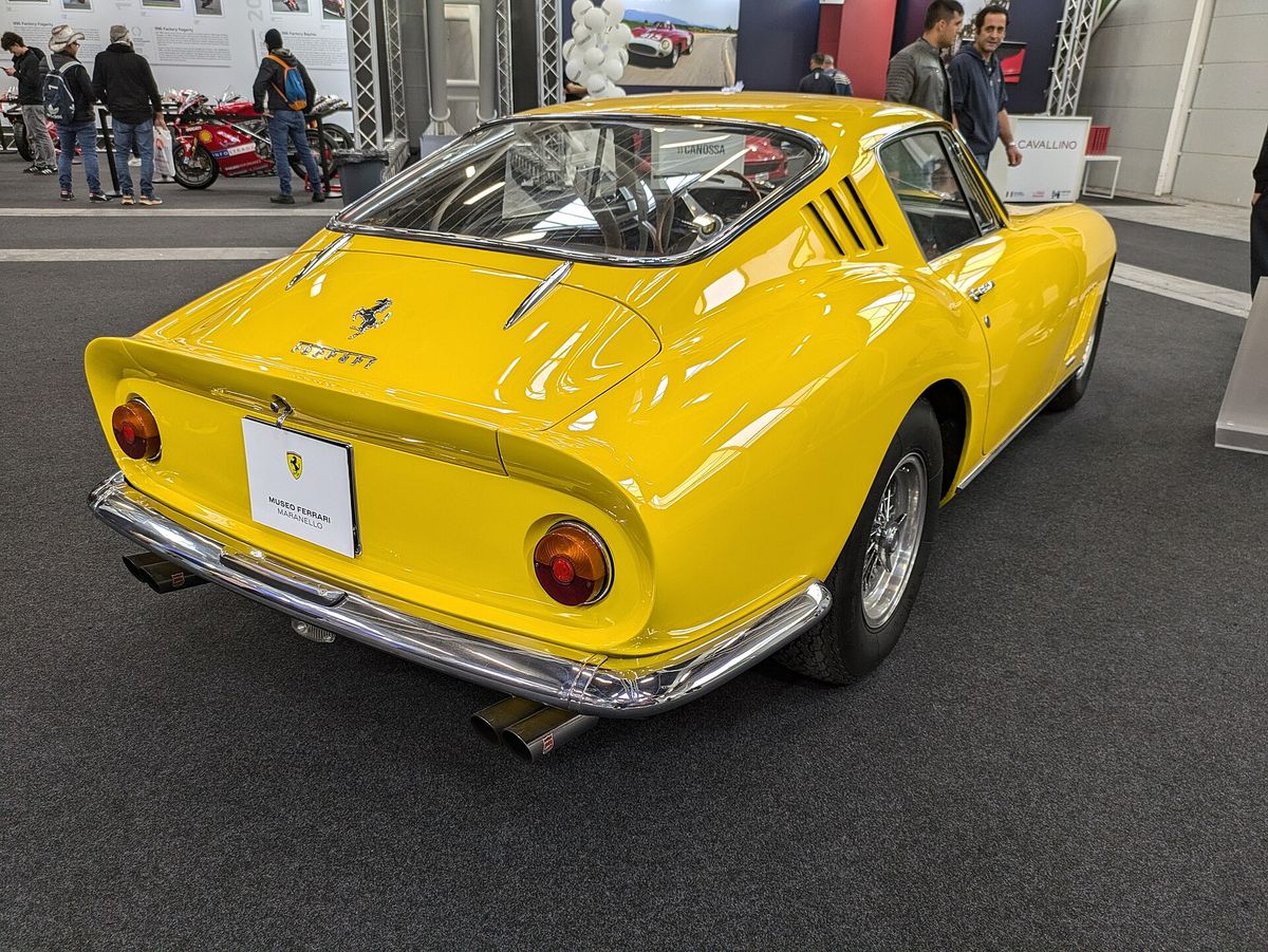 A Ferrari 275 GTB coupe on display in a museum, photographed in three-quarter front view against a plain background.