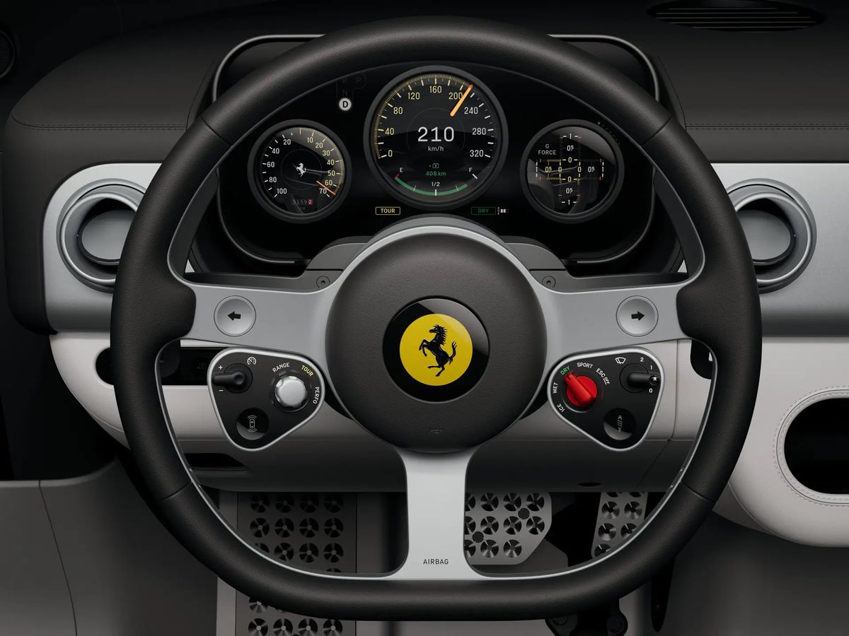 The Ferrari Luce steering wheel and instrument binnacle, showing three round analogue style dials behind a wheel carrying the prancing horse badge and a red starter control.