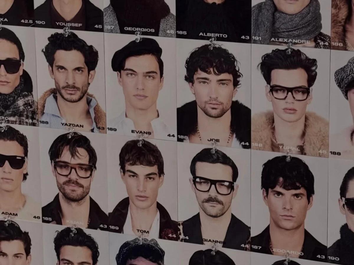 A casting wall covered in grids of headshots of young male models, each pinned with a name and measurement card beneath it.