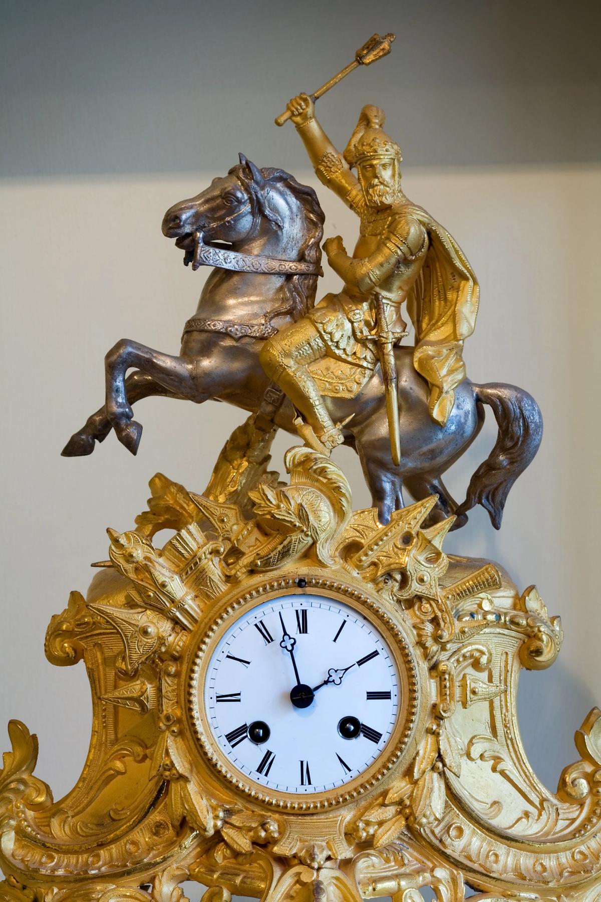 An ornate vintage mantel clock with a decorated case and metal dial.