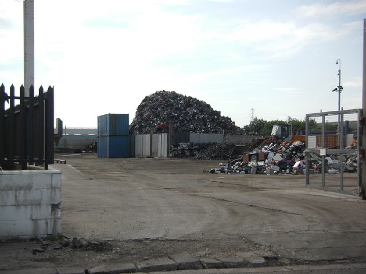 A scrap metal yard piled with crushed and sorted metal awaiting processing.
